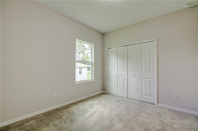 unfurnished bedroom with light carpet and a closet