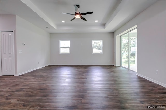 spare room with dark hardwood / wood-style floors, ceiling fan, and a raised ceiling