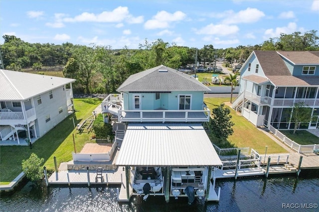 rear view of house with a water view, a lawn, and boat lift