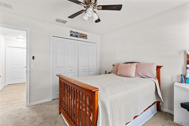 bedroom featuring visible vents, a ceiling fan, light colored carpet, and a closet