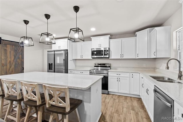 kitchen featuring a sink, a center island, light wood-style flooring, white cabinetry, and appliances with stainless steel finishes