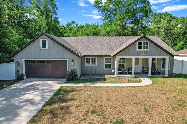 view of front of property featuring board and batten siding, a front yard, an attached garage, fence, and a porch
