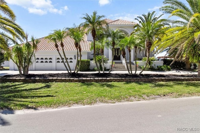 view of front of property with a tile roof, an attached garage, and stucco siding