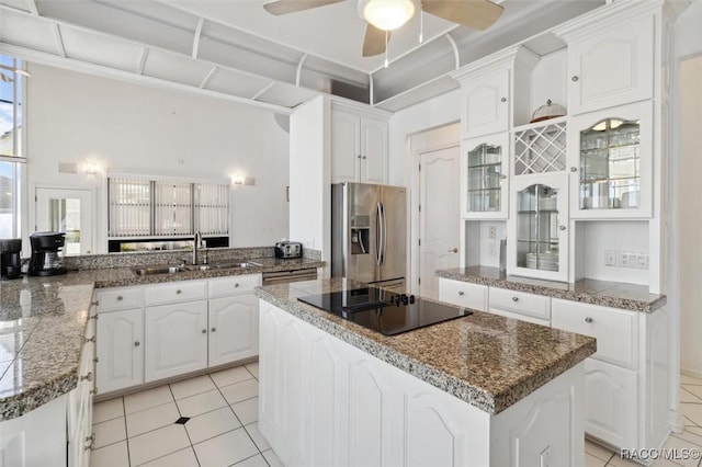 kitchen featuring a ceiling fan, a sink, a center island, stainless steel fridge, and black electric cooktop