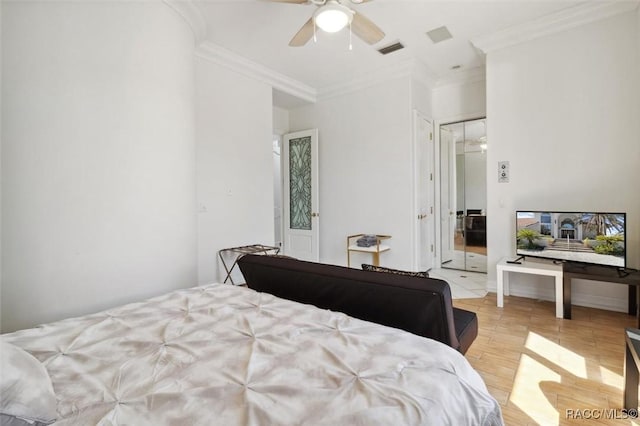 bedroom featuring light wood finished floors, visible vents, crown molding, and a ceiling fan