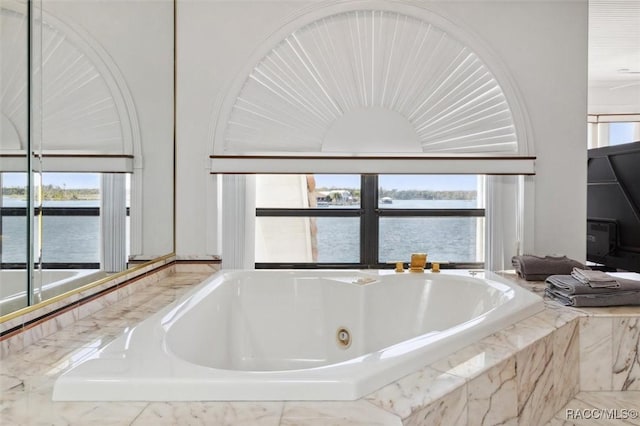 bathroom with a jetted tub and a water view