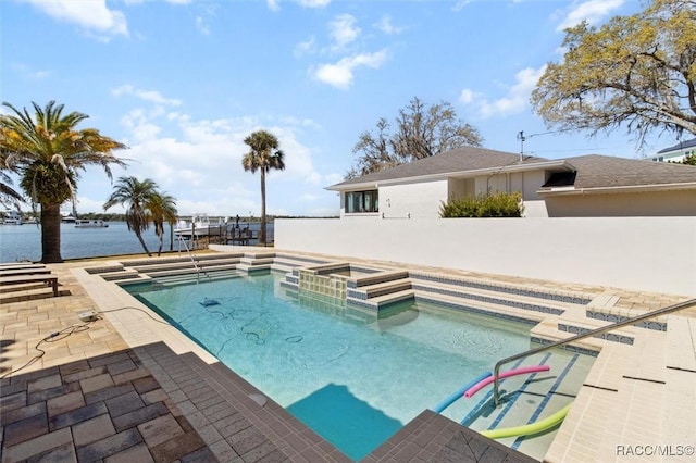 pool featuring a patio, an in ground hot tub, and a water view