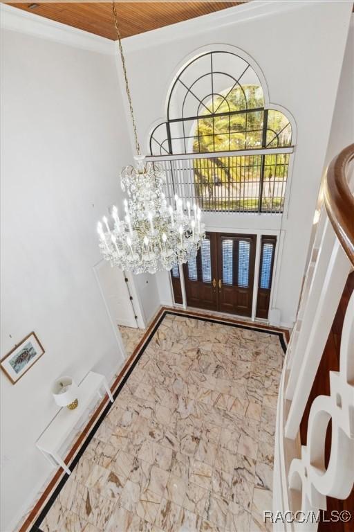 foyer entrance featuring an inviting chandelier, french doors, and marble finish floor