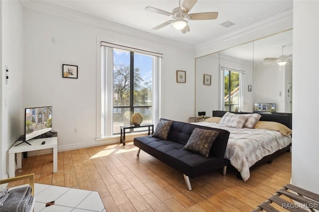 bedroom with visible vents, baseboards, ornamental molding, light wood-style floors, and a ceiling fan