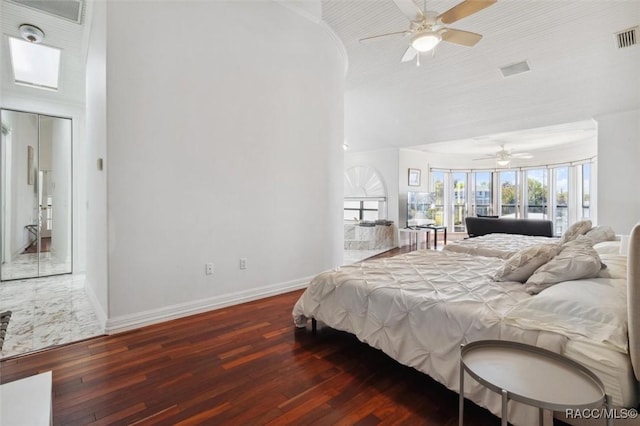 bedroom featuring a ceiling fan, wood finished floors, baseboards, a high ceiling, and access to outside