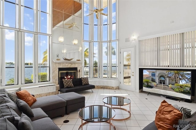 tiled living room with visible vents, a water view, a high ceiling, and a fireplace