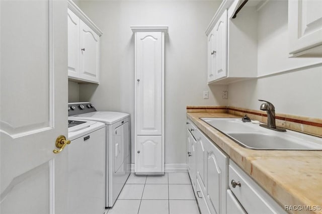 laundry area featuring cabinet space, light tile patterned floors, washer and dryer, and a sink