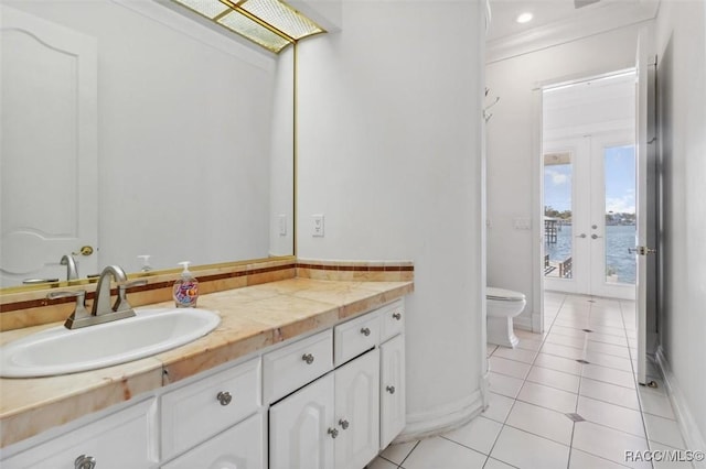 bathroom with toilet, french doors, tile patterned flooring, baseboards, and vanity