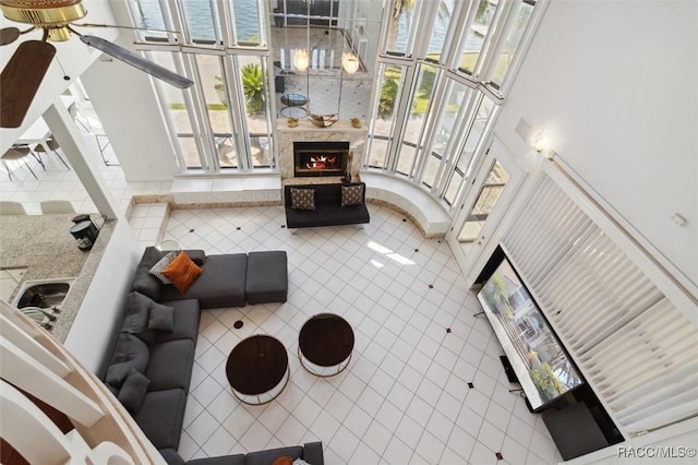 living room with tile patterned floors, a high end fireplace, and a ceiling fan