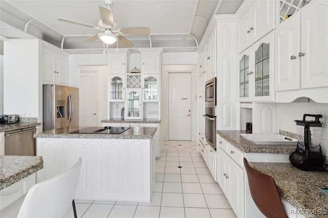 kitchen with white cabinets, appliances with stainless steel finishes, a center island, and glass insert cabinets