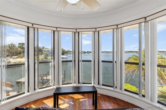 sunroom / solarium featuring a ceiling fan, a water view, and a wealth of natural light