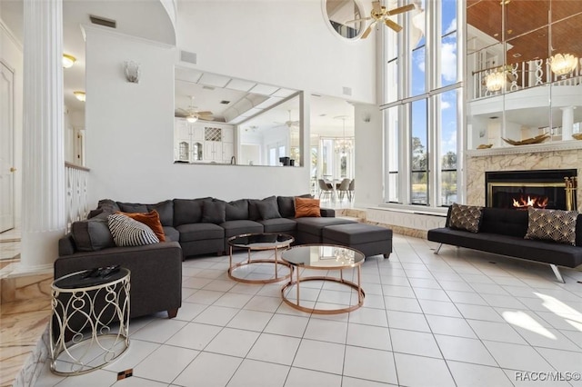 tiled living room featuring a high end fireplace, visible vents, and ceiling fan