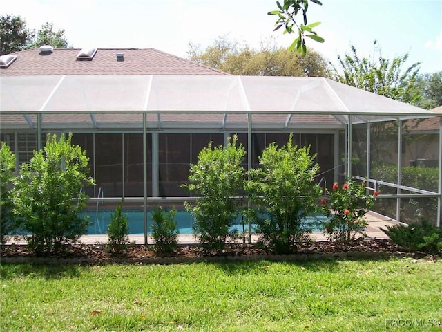 back of house featuring a lanai and a yard