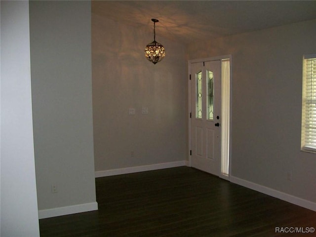 entrance foyer with an inviting chandelier and dark hardwood / wood-style floors