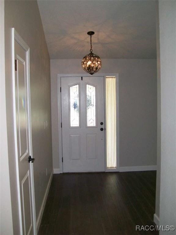 foyer entrance with dark wood-type flooring and a notable chandelier