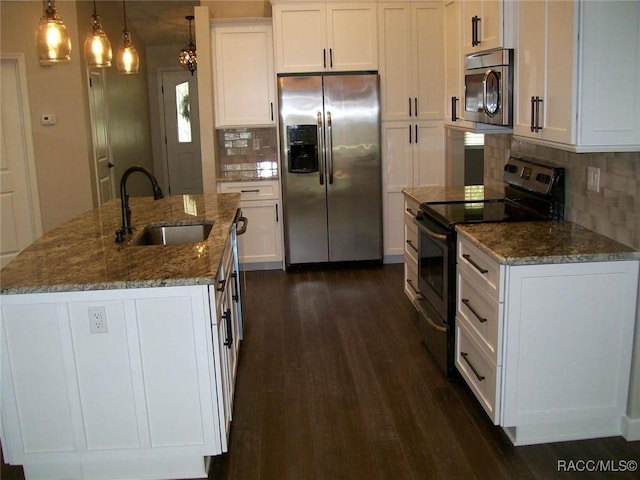 kitchen featuring sink, white cabinetry, dark stone counters, stainless steel appliances, and a kitchen island with sink