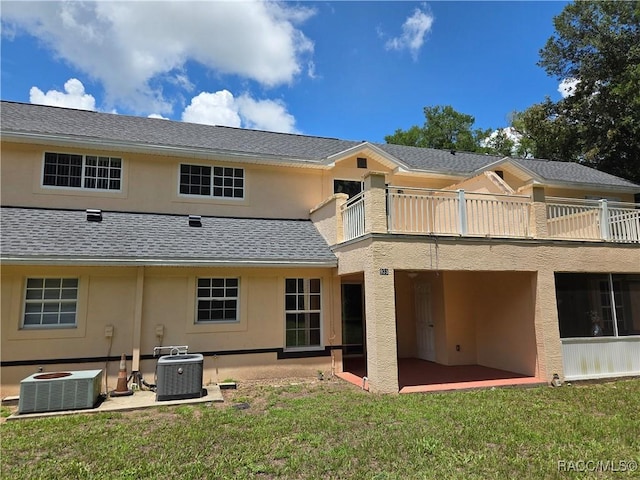 933 N Rembrandt Way, Inverness, FL 34453 - back of property with a balcony, a patio area, stucco siding, a lawn, and a shingled roof