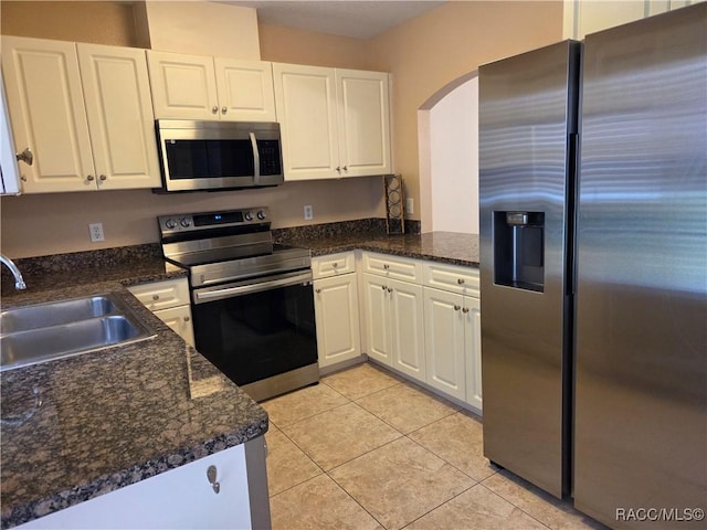 933 N Rembrandt Way, Inverness, FL 34453 - kitchen with stainless steel appliances, arched walkways, white cabinets, and light tile patterned floors