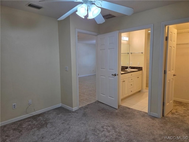 933 N Rembrandt Way, Inverness, FL 34453 - unfurnished bedroom featuring light colored carpet, a walk in closet, light tile patterned floors, and connected bathroom