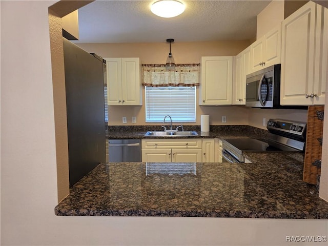 933 N Rembrandt Way, Inverness, FL 34453 - kitchen with appliances with stainless steel finishes, white cabinets, a peninsula, dark stone countertops, and a textured ceiling