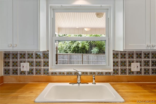 interior space with white cabinets, decorative backsplash, and sink