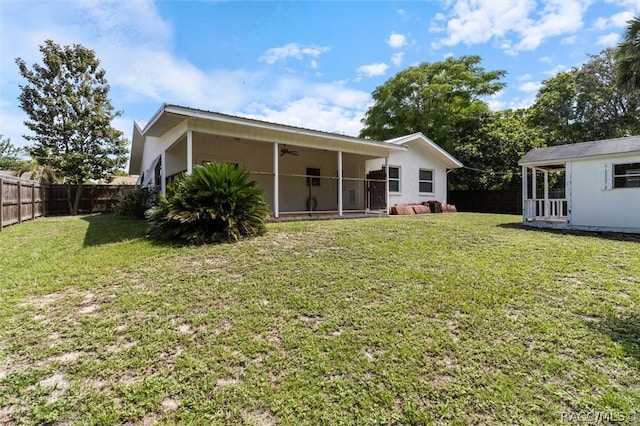 rear view of house featuring ceiling fan and a yard