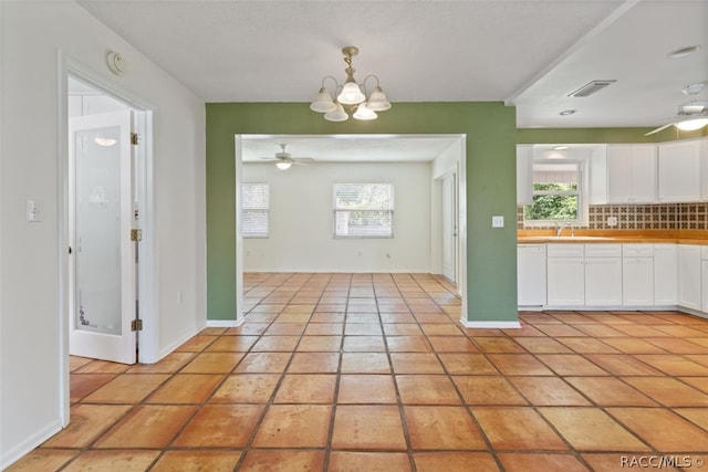 interior space with sink, light tile patterned floors, and ceiling fan with notable chandelier