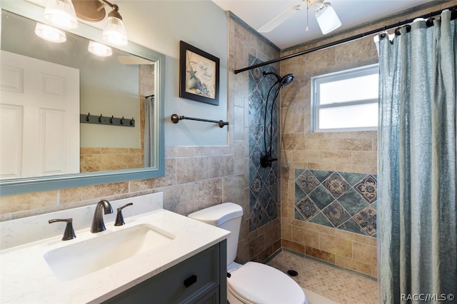 bathroom with vanity, ceiling fan, tile walls, toilet, and curtained shower