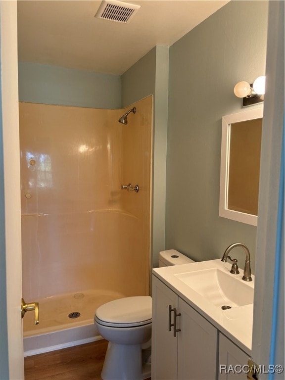 bathroom with a shower, vanity, wood-type flooring, and toilet