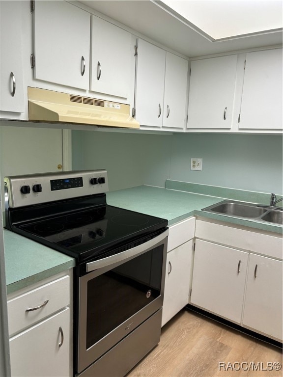 kitchen with white cabinets, stainless steel electric range oven, sink, and light hardwood / wood-style flooring