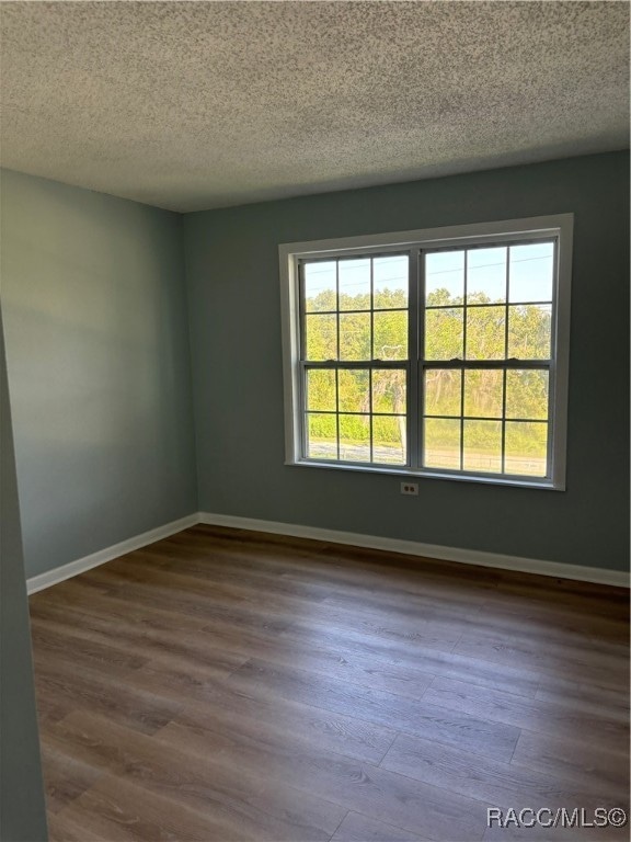 unfurnished room with a wealth of natural light, a textured ceiling, and hardwood / wood-style flooring