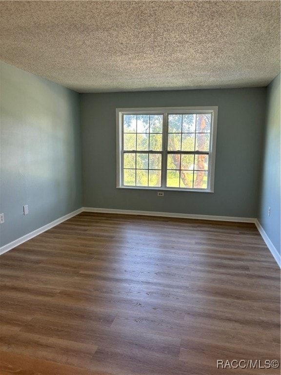 empty room with a textured ceiling and dark wood-type flooring