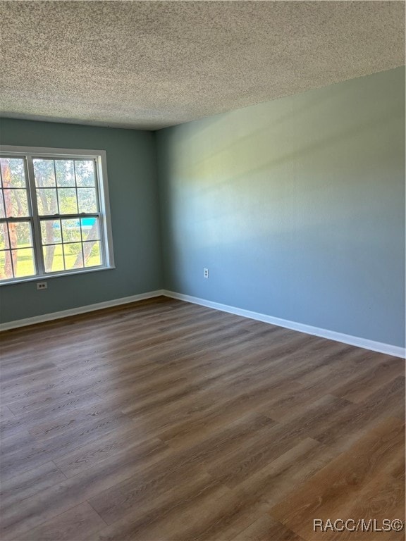 unfurnished room featuring a textured ceiling and dark wood-type flooring