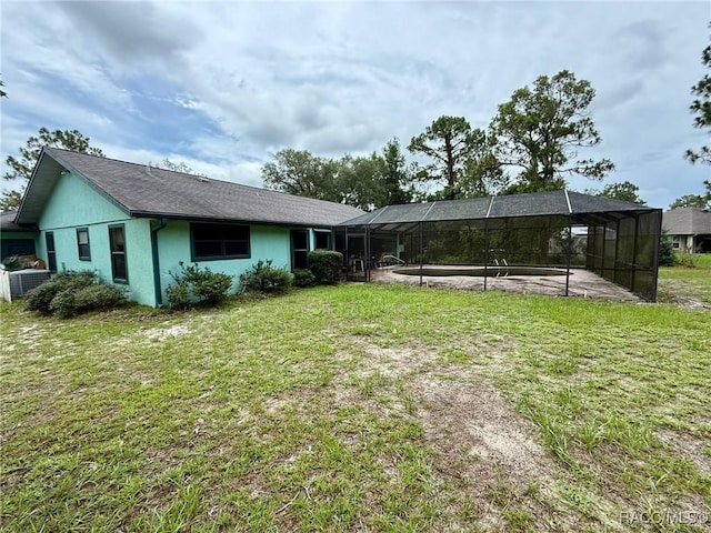 2750 W Mustang Blvd, Beverly Hills, FL 34465 - rear view of house featuring a lawn, glass enclosure, and stucco siding