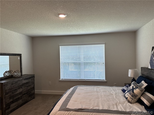 bedroom featuring dark colored carpet and a textured ceiling