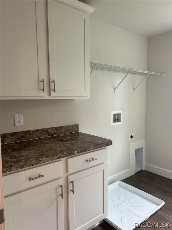 clothes washing area with hookup for an electric dryer, hookup for a washing machine, dark hardwood / wood-style flooring, and cabinets