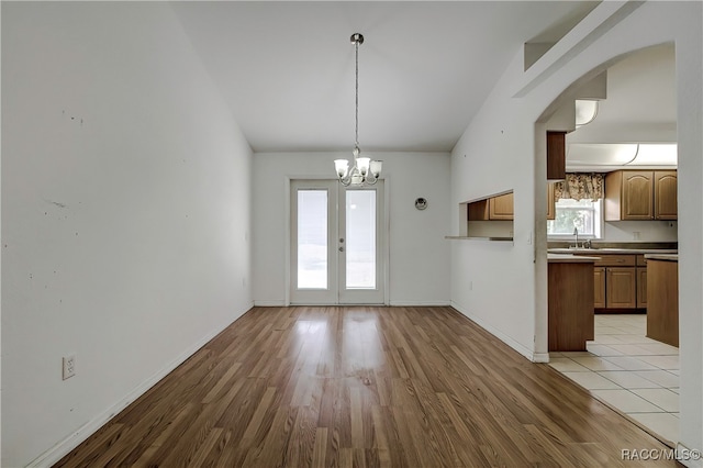 kitchen with pendant lighting, an inviting chandelier, french doors, sink, and light wood-type flooring