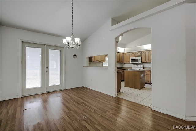 kitchen featuring french doors, white appliances, pendant lighting, light hardwood / wood-style flooring, and lofted ceiling