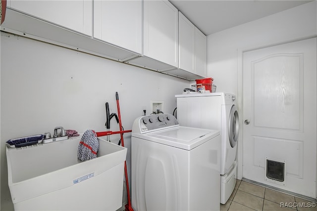 clothes washing area featuring separate washer and dryer, sink, light tile patterned floors, and cabinets