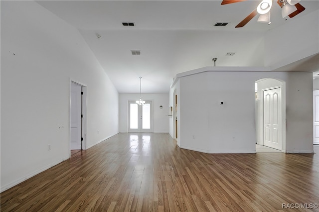 unfurnished living room featuring french doors, hardwood / wood-style floors, high vaulted ceiling, and ceiling fan with notable chandelier