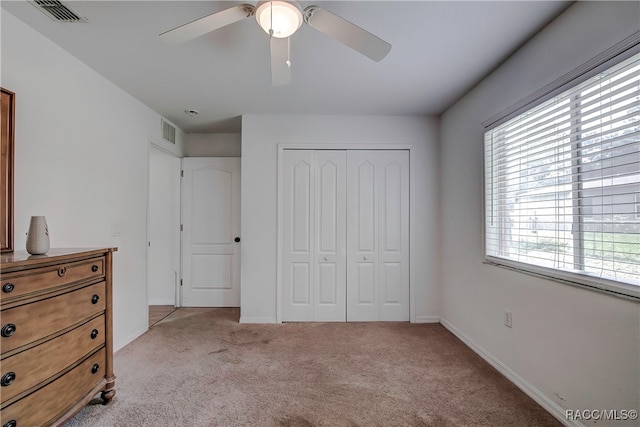 bedroom with a closet, ceiling fan, and light colored carpet