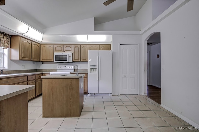 kitchen with light tile patterned floors, white appliances, a center island, and lofted ceiling