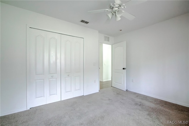 unfurnished bedroom featuring light colored carpet, a closet, and ceiling fan