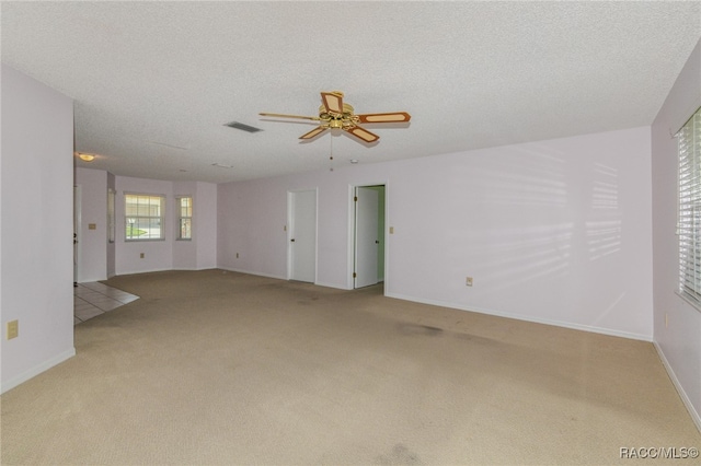 unfurnished room featuring ceiling fan, light colored carpet, and a textured ceiling