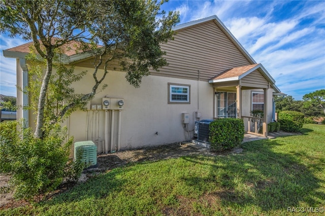 back of property with a lawn and central AC